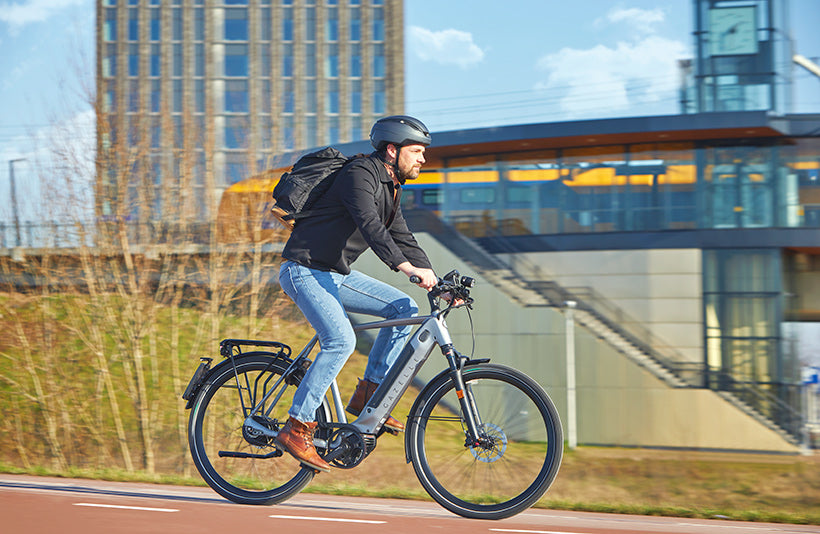 Man riding a hybrid electric bicycle in an urban environment.