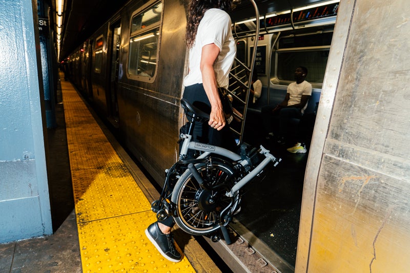 A woman takes a folding bicycle on the underground.
