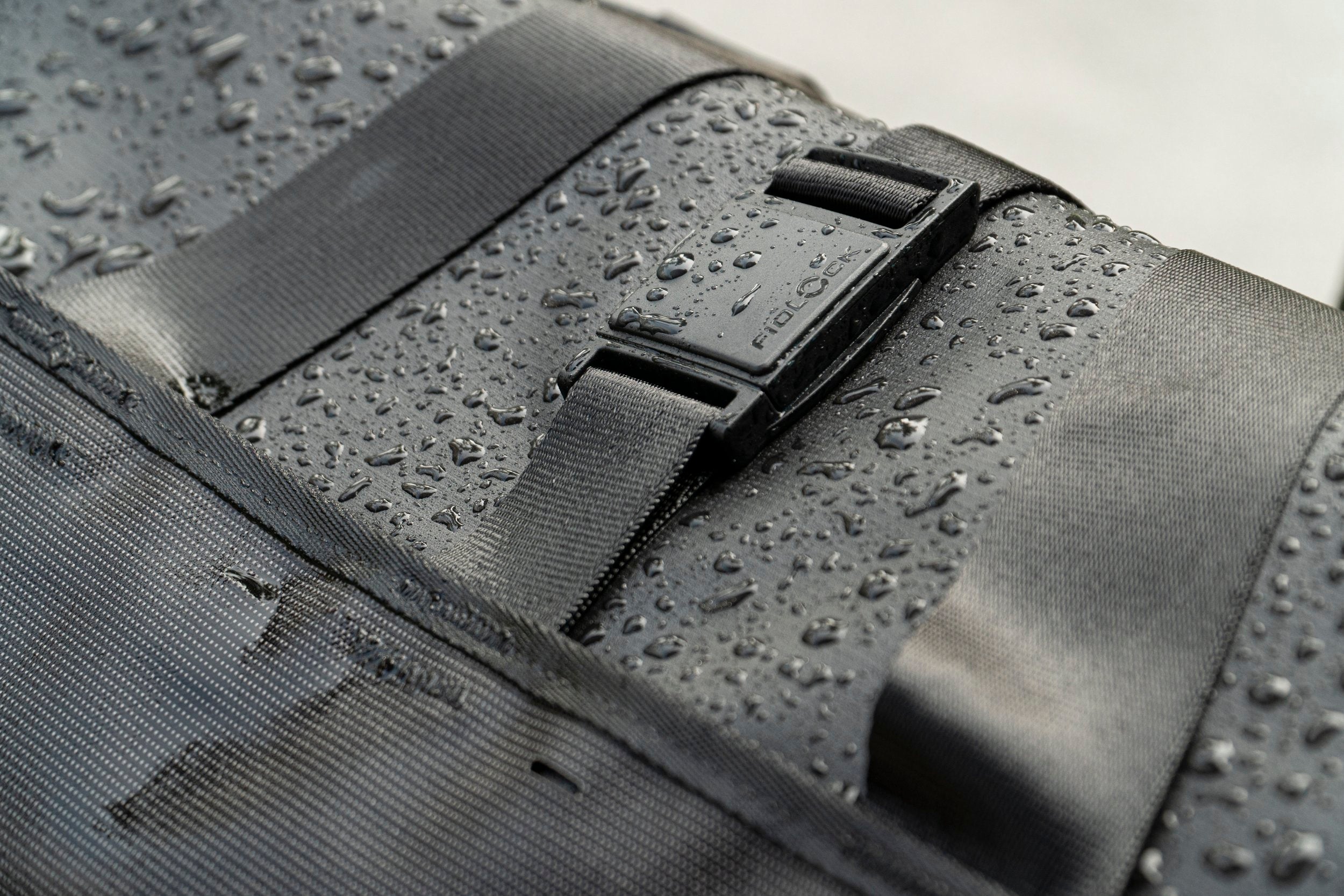 Black bike pannier with water droplets on a textured surface