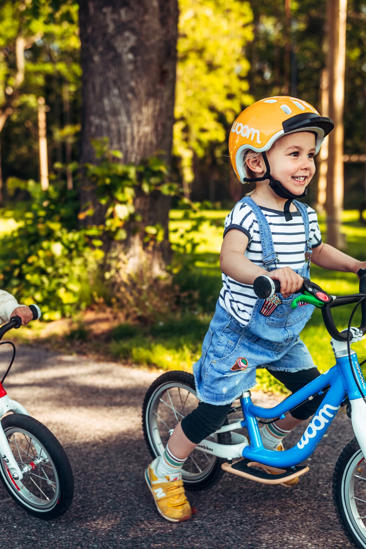 Child riding a blue Woom balance bicycle with a helmet in a park setting