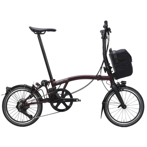 Purple Brompton folding bicycle with a black bag on a white background