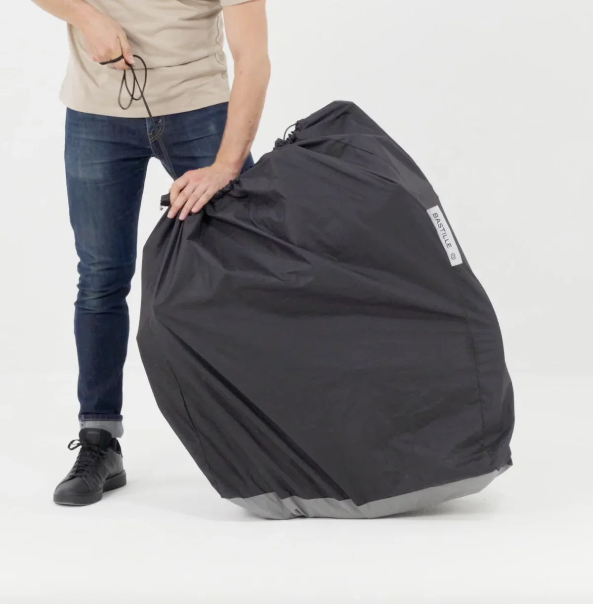 Person holding a large black and grey bag with a visible Bastille brand logo on a white background