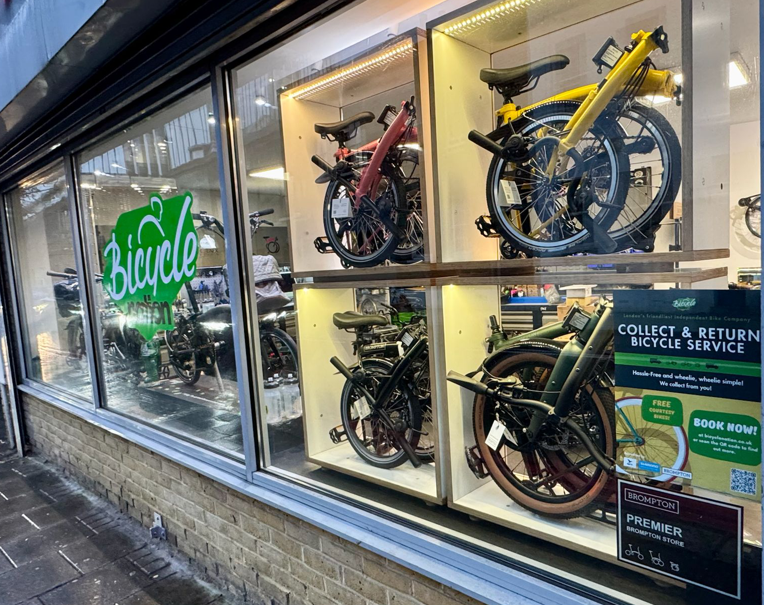 Display of bicycles in a store window with promotional signs.