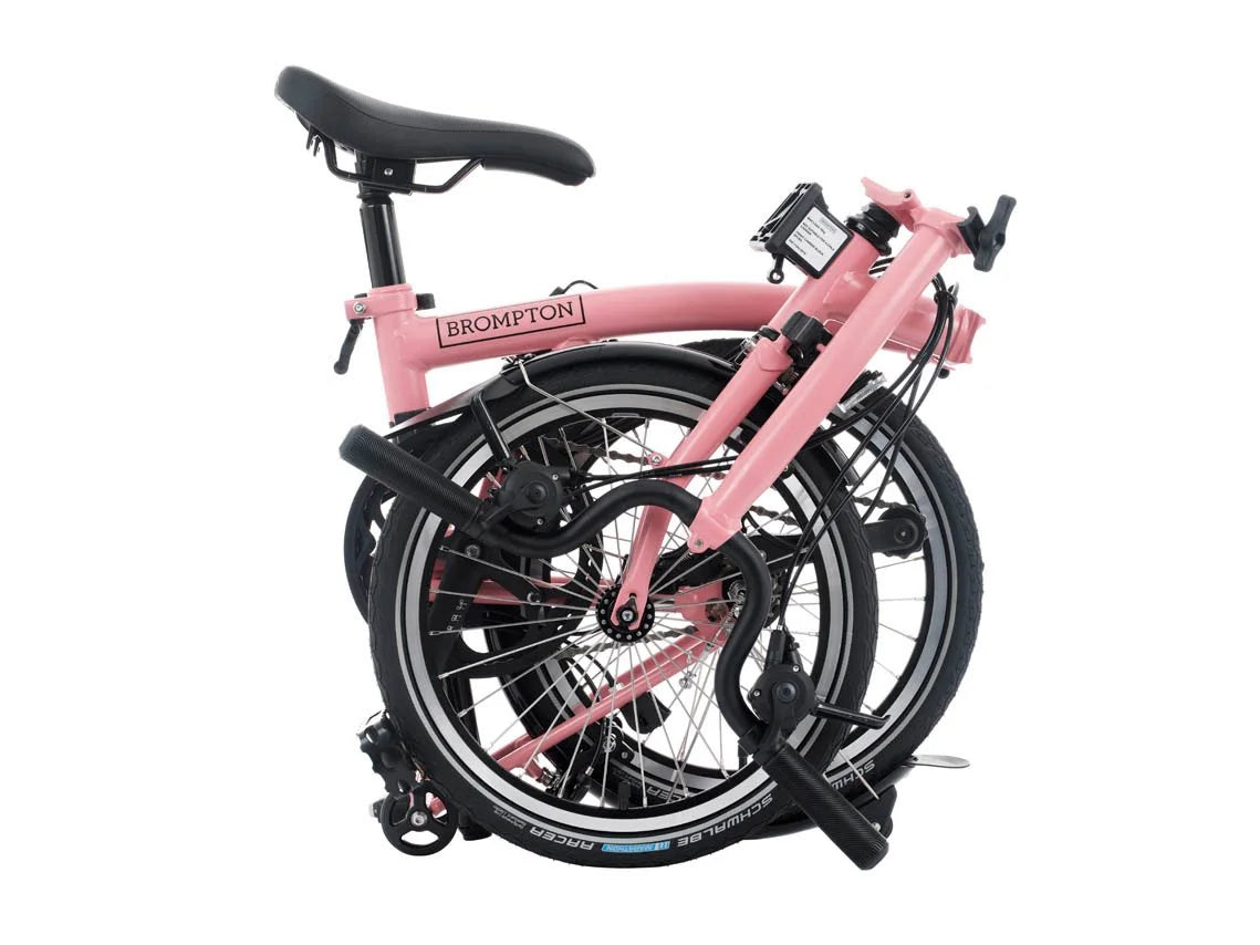 Pink folding bicycle with 'Brompton' branding on a white background