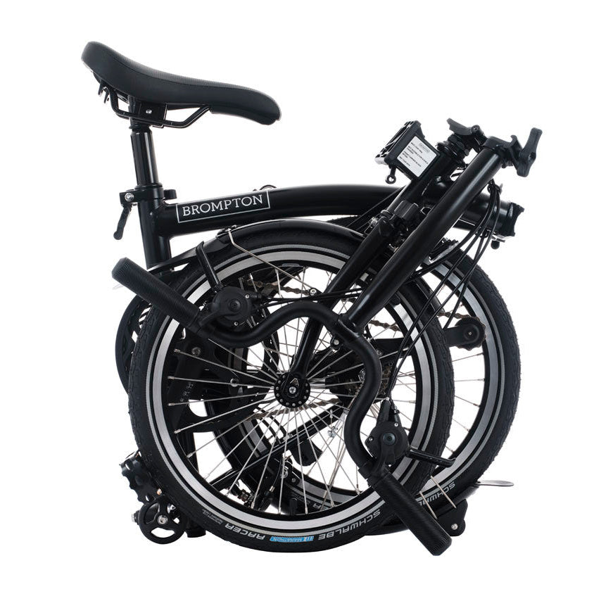 Folded black bicycle with 'Brompton' branding on a white background