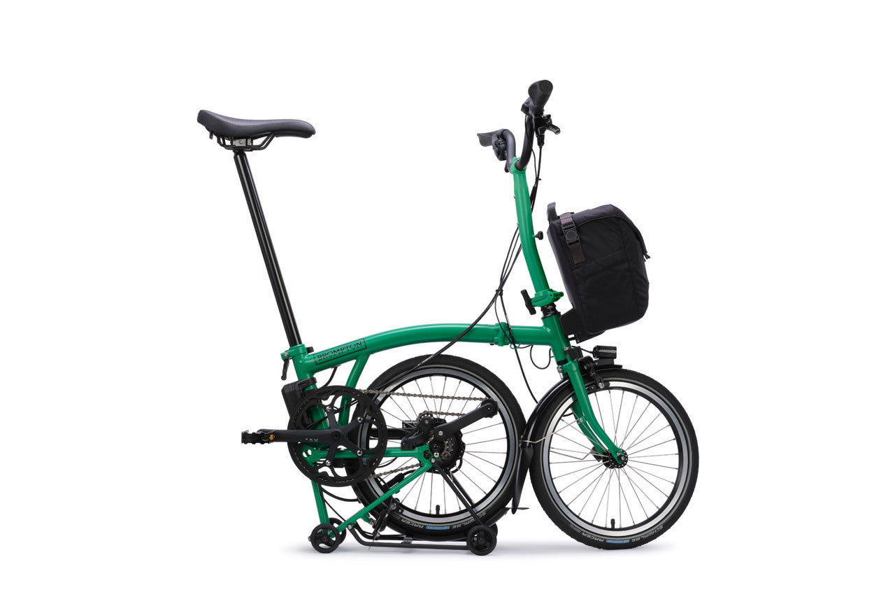 Green folding bicycle with a black basket on a white background
