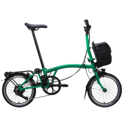 Green Brompton folding bicycle with a black bag on a white background