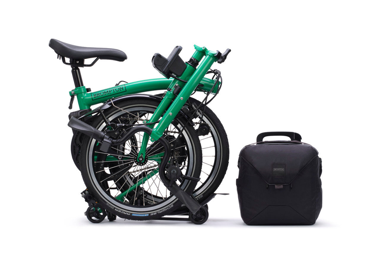 Green folded bike with a black bag on a white background