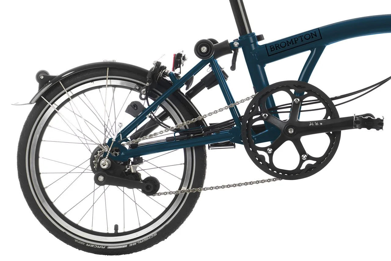 Close-up of a blue Brompton folding bicycle with visible branding on a white background