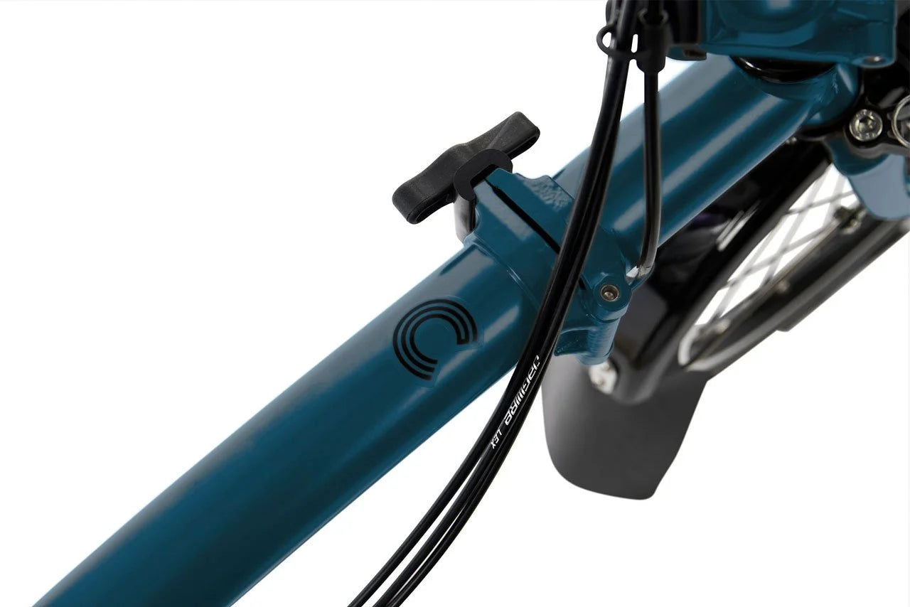 Close-up of a blue Brompton bicycle with a black logo on a white background