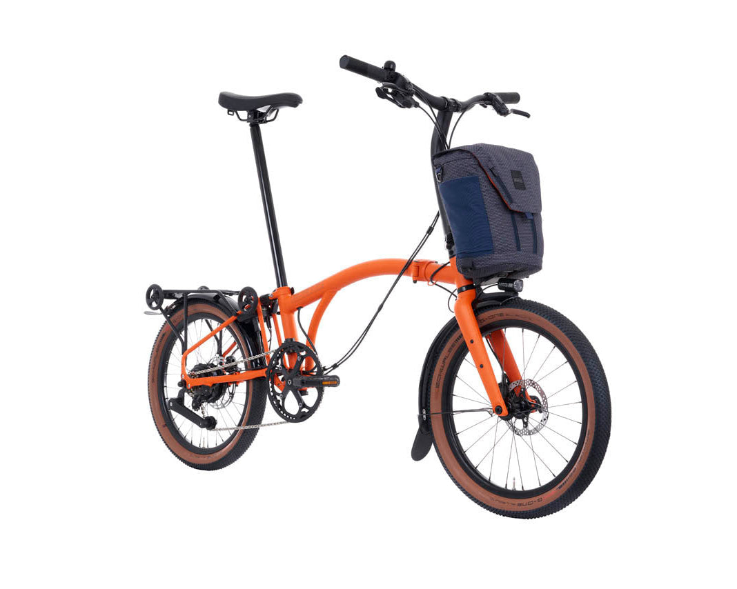Orange Brompton g Line electric bike with a black basket on a white background