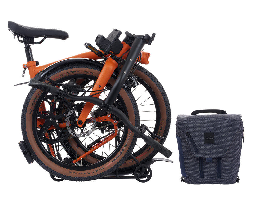 Orange Brompton G Line Electric folding bicycle with a blue backpack on a white background