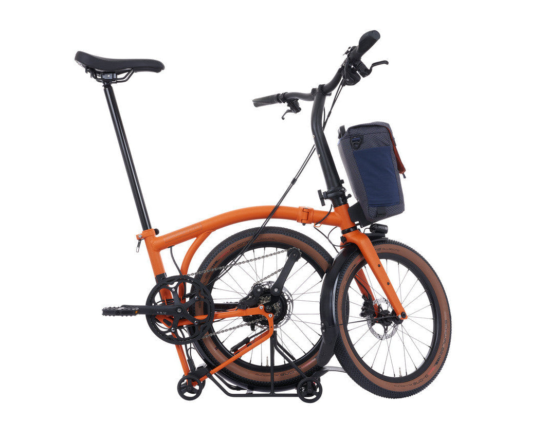 Orange brompton g line electric folding bicycle with a blue bag on a white background