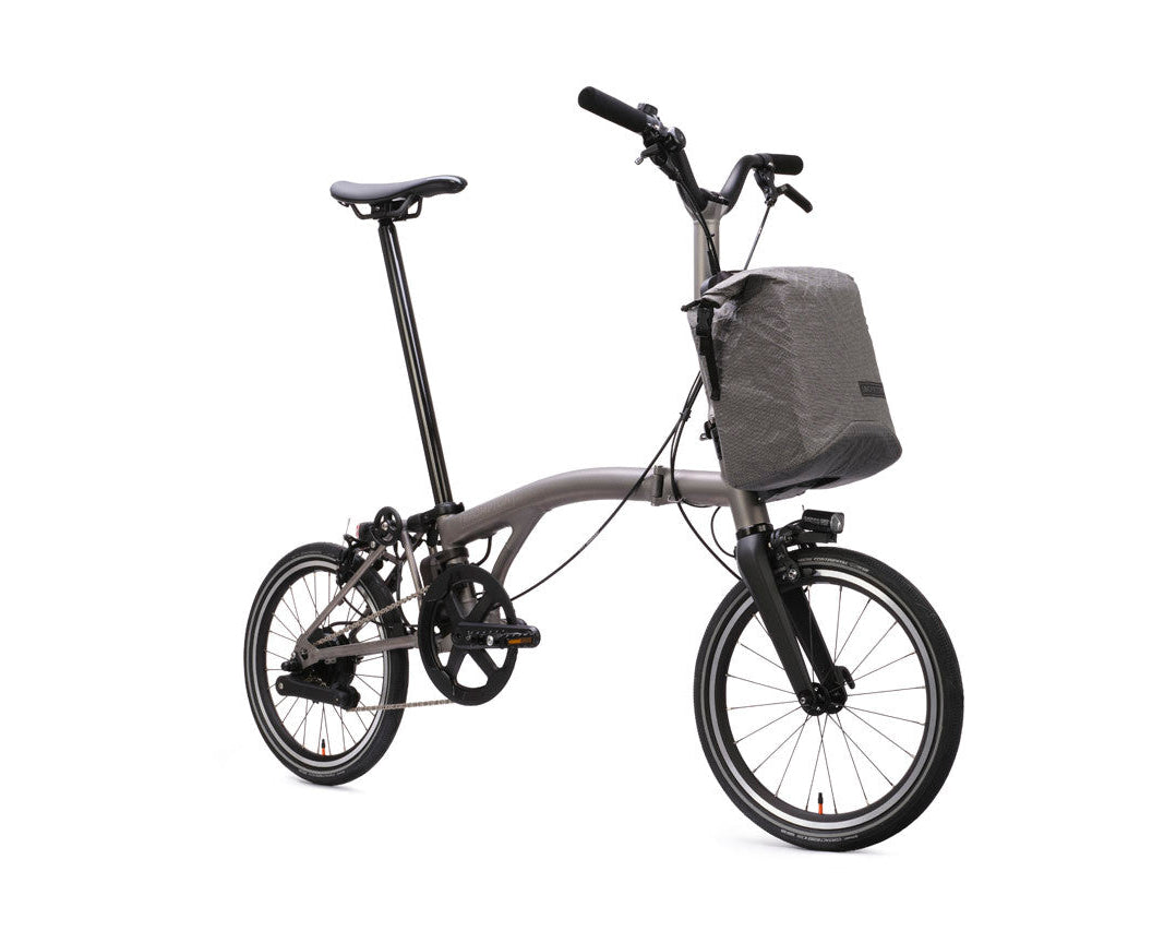 Brompton Electric T Line bicycle with a front bag on a white background