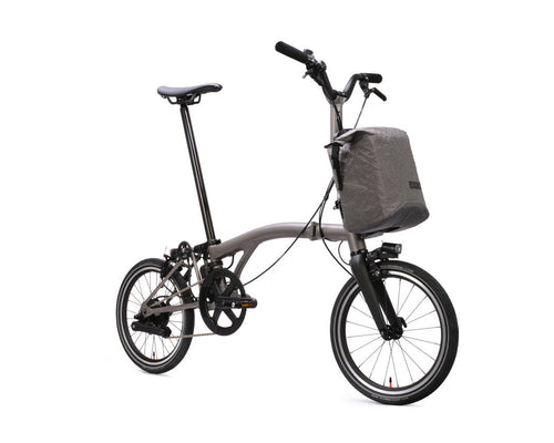 Brompton Electric T Line bicycle with a front bag on a white background