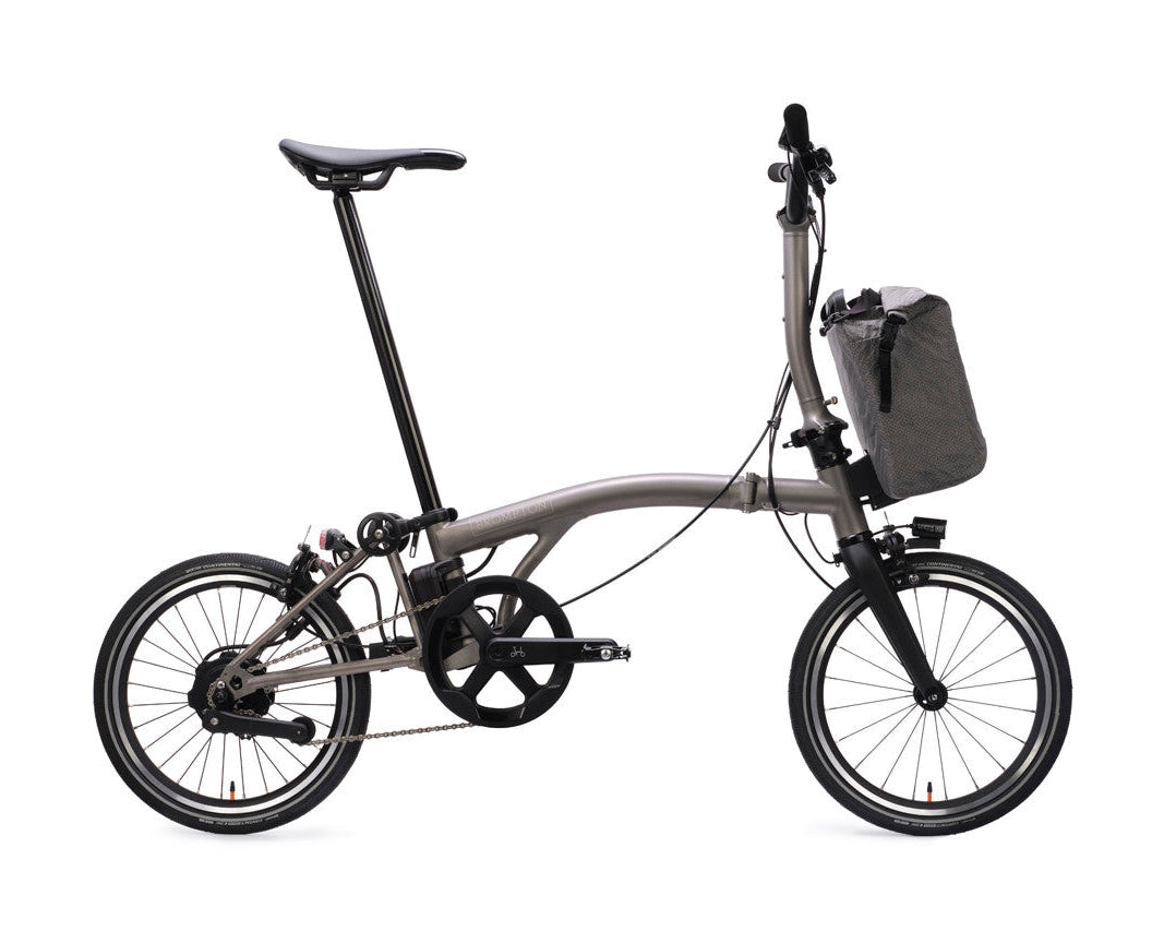Foldable Brompton Electric T Line bicycle with a front storage bag on a white background