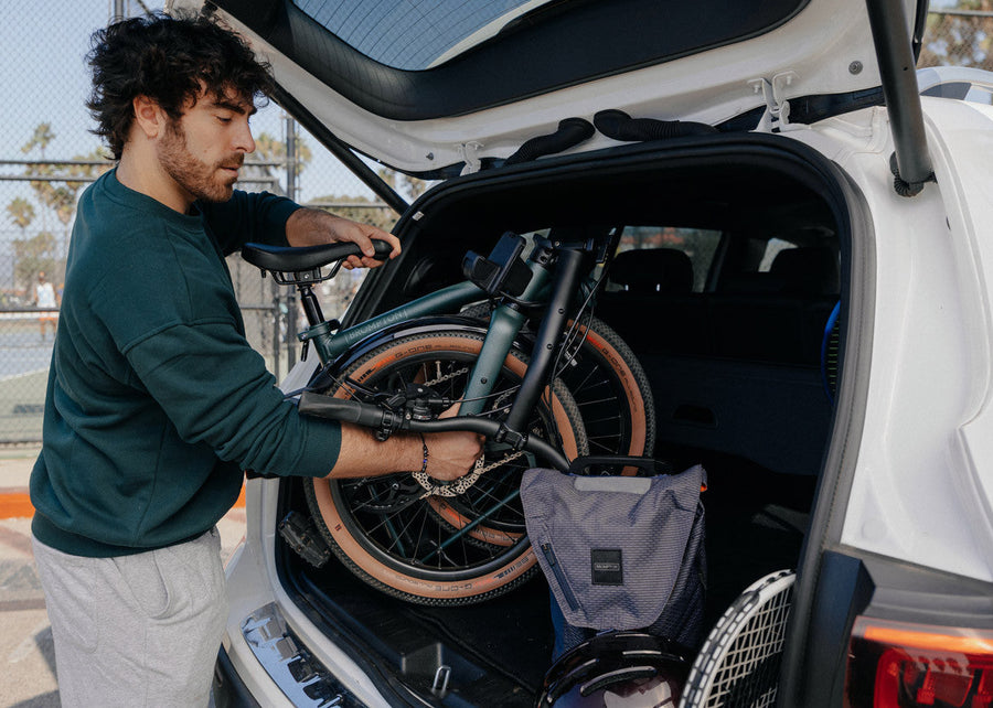 A person loading the Brompton G Line folding bike to the white car.