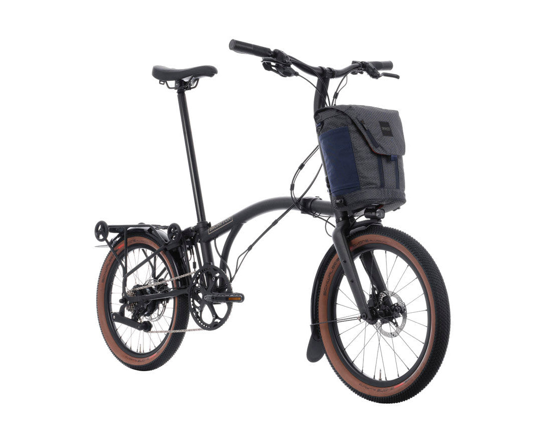 Black Brompton g Line electric bike with a basket on a white background