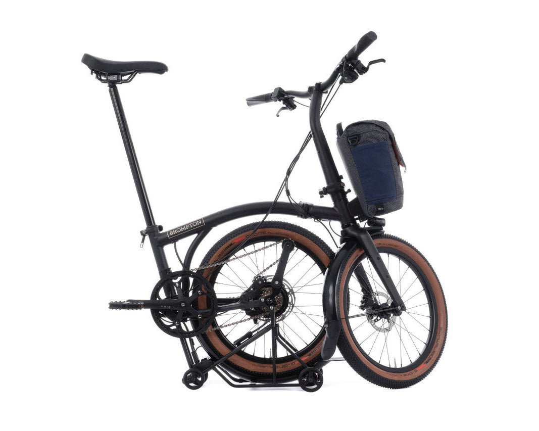 Foldable Brompton G Line electric bicycle with a bag on a white background