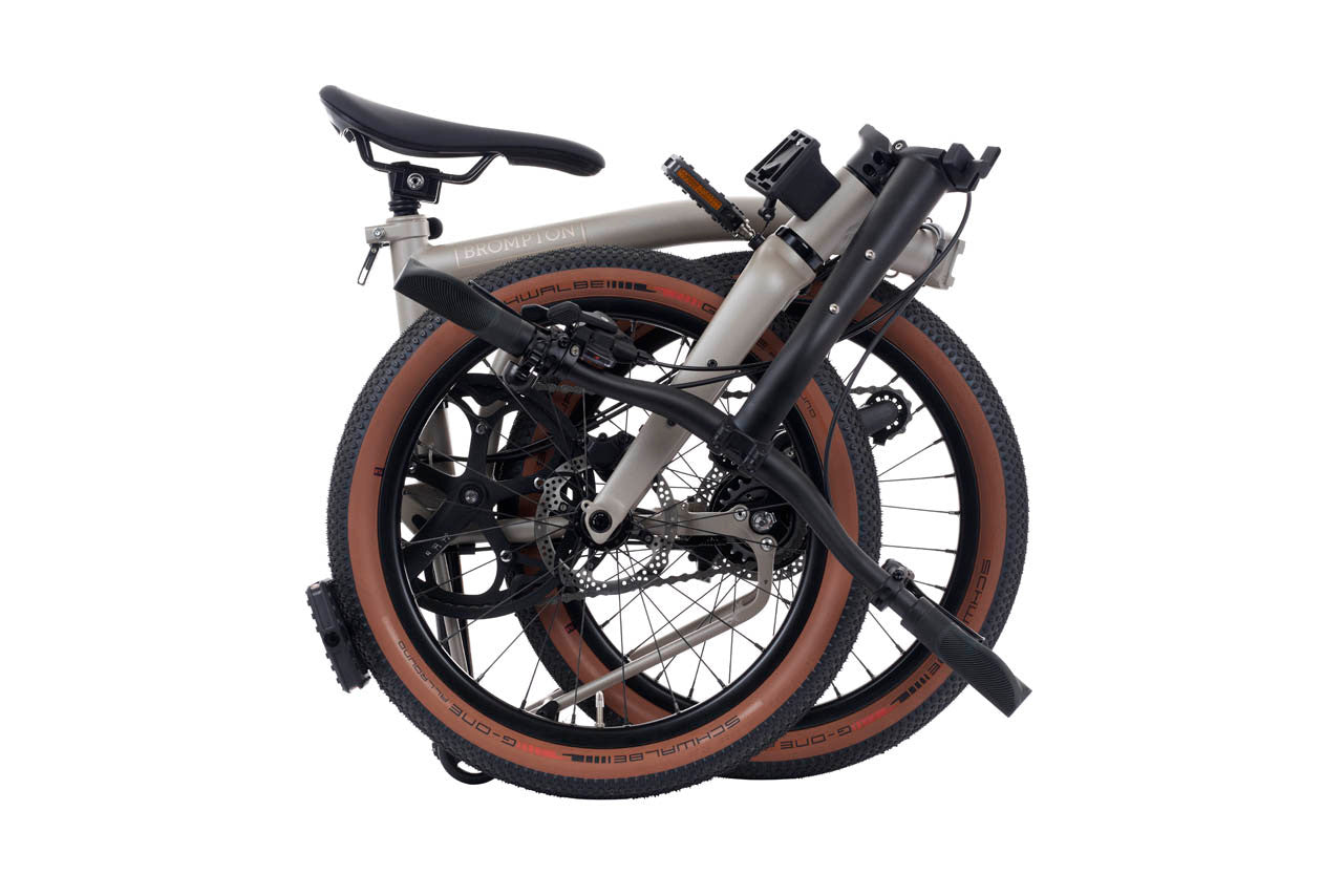 Folded bicycle with brown tires on a white background