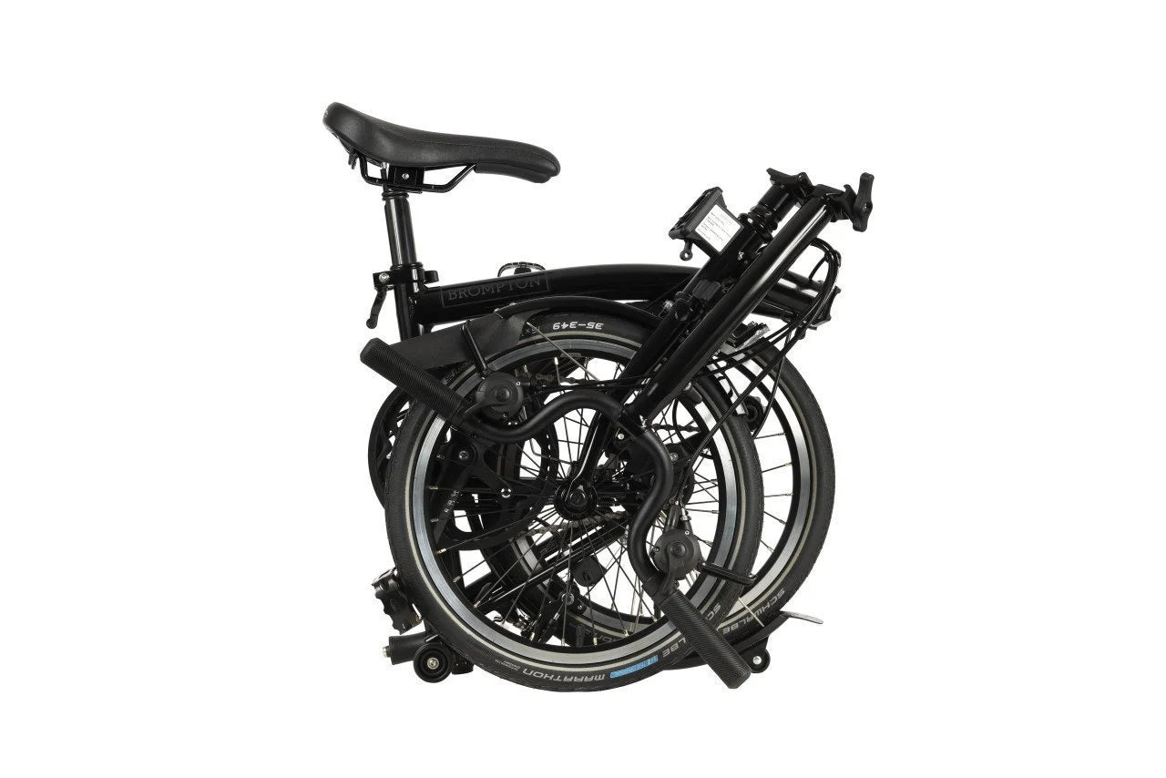 Black Brompton folded bike on the white background.