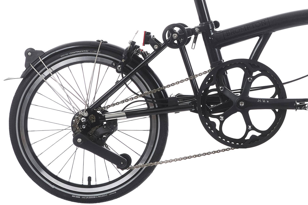 Close-up of a black bicycle wheel and chain on a white background