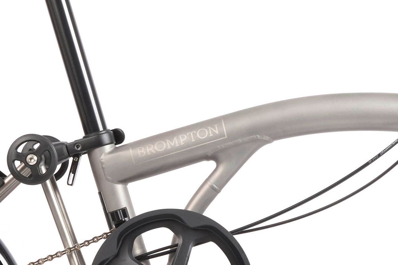 Close-up of a bicycle frame with 'Brompton' branding on a white background