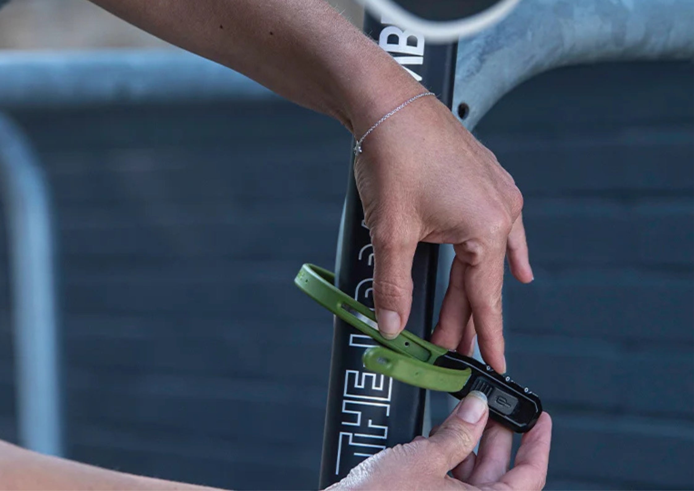 Person holding a green  'Hiplok' branded ziplock style lock near a bicycle.