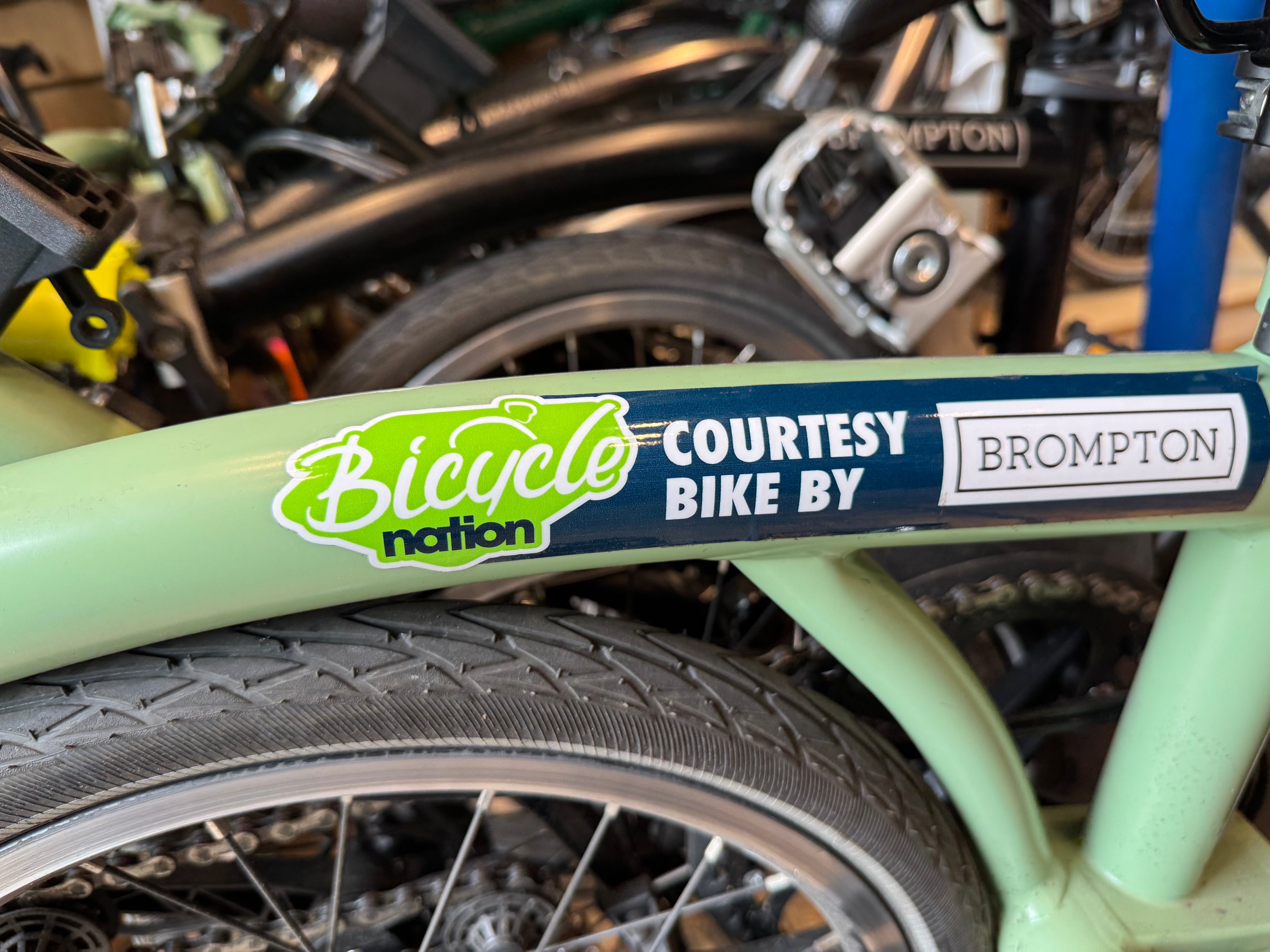Bicycle with 'Bicycle Nation' and 'Brompton' stickers on a blurred background