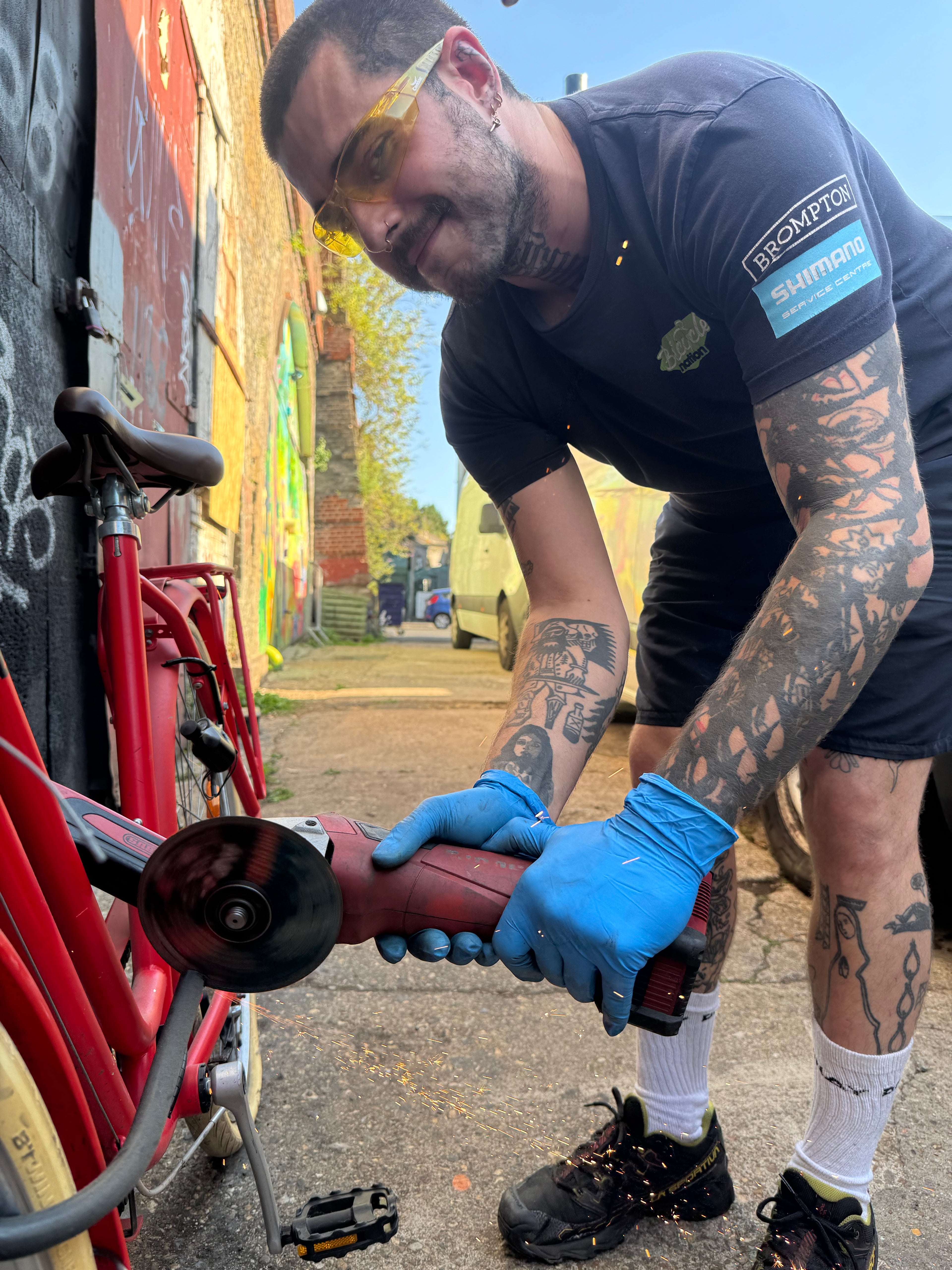 Person using a grinder on a vehicle with tattoos visible