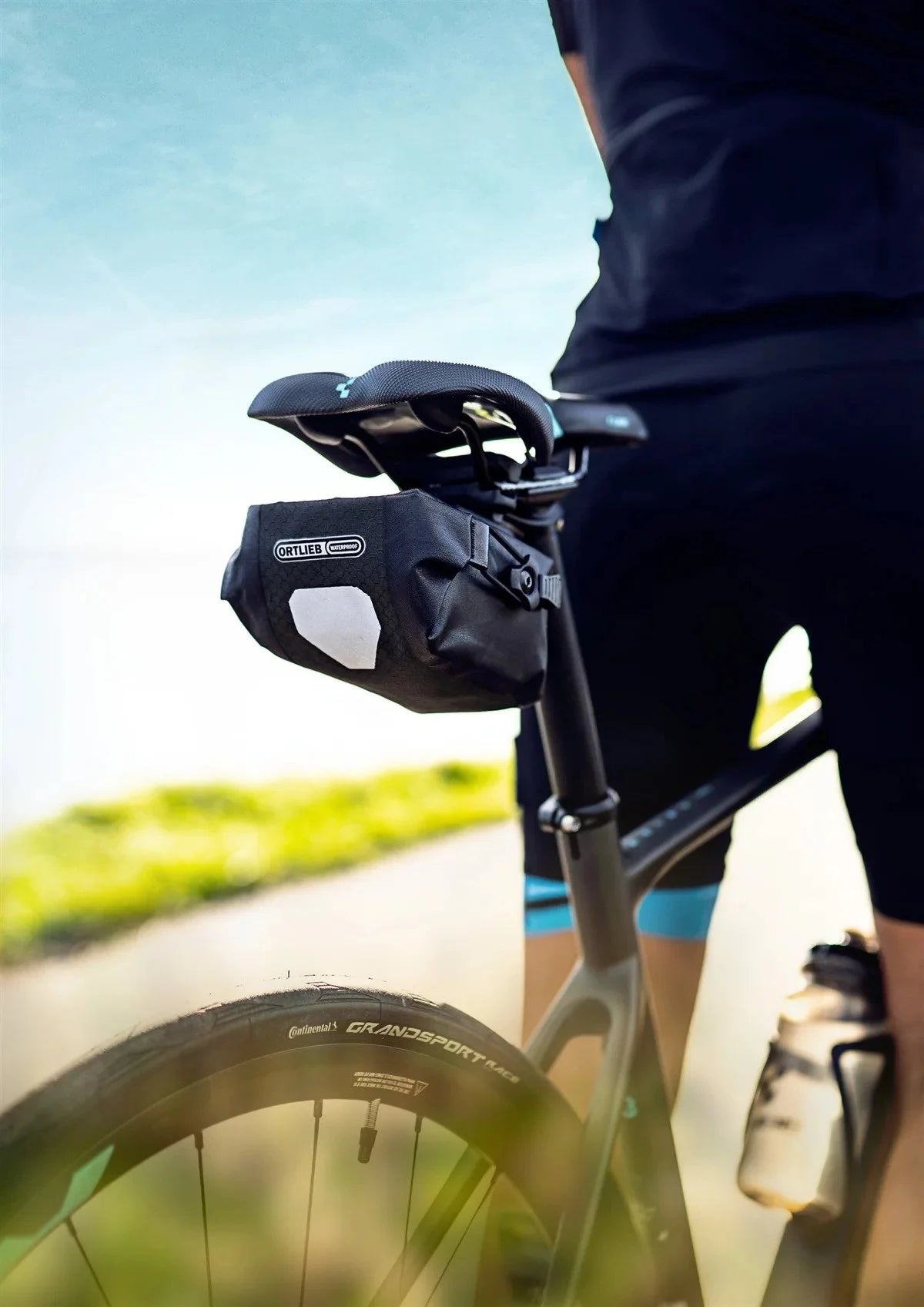 Ortlieb saddle bag on a bicycle with rider partially visible.