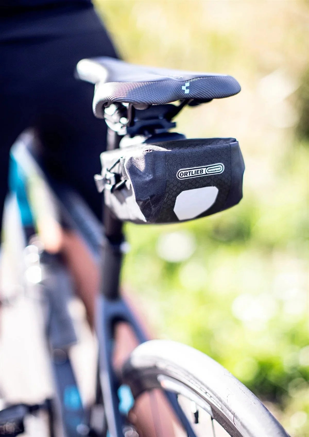 Bicycle seat with a black Ortlieb bag attached, blurred background