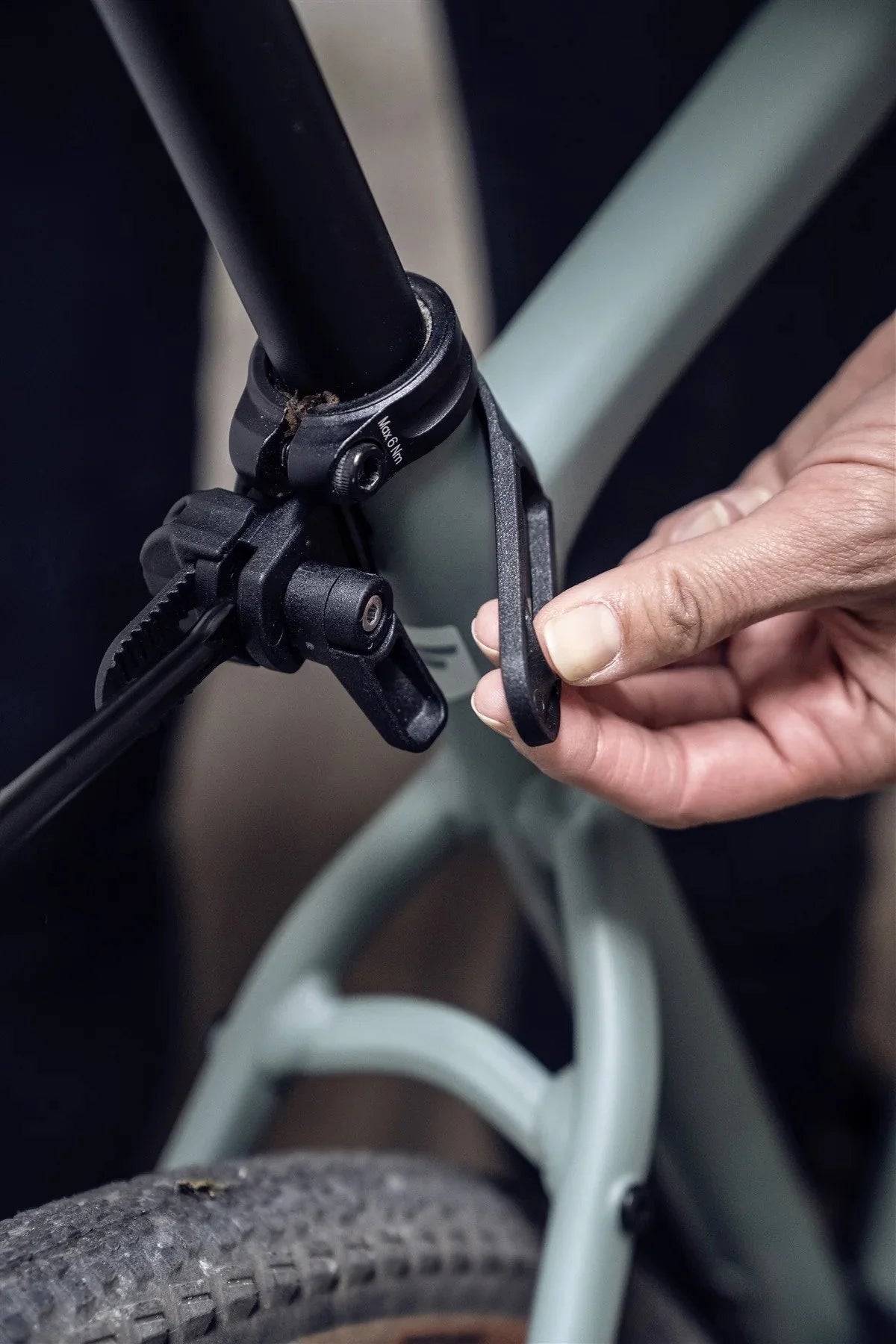 Close-up of a hand adjusting a bicycle part to the seat post.