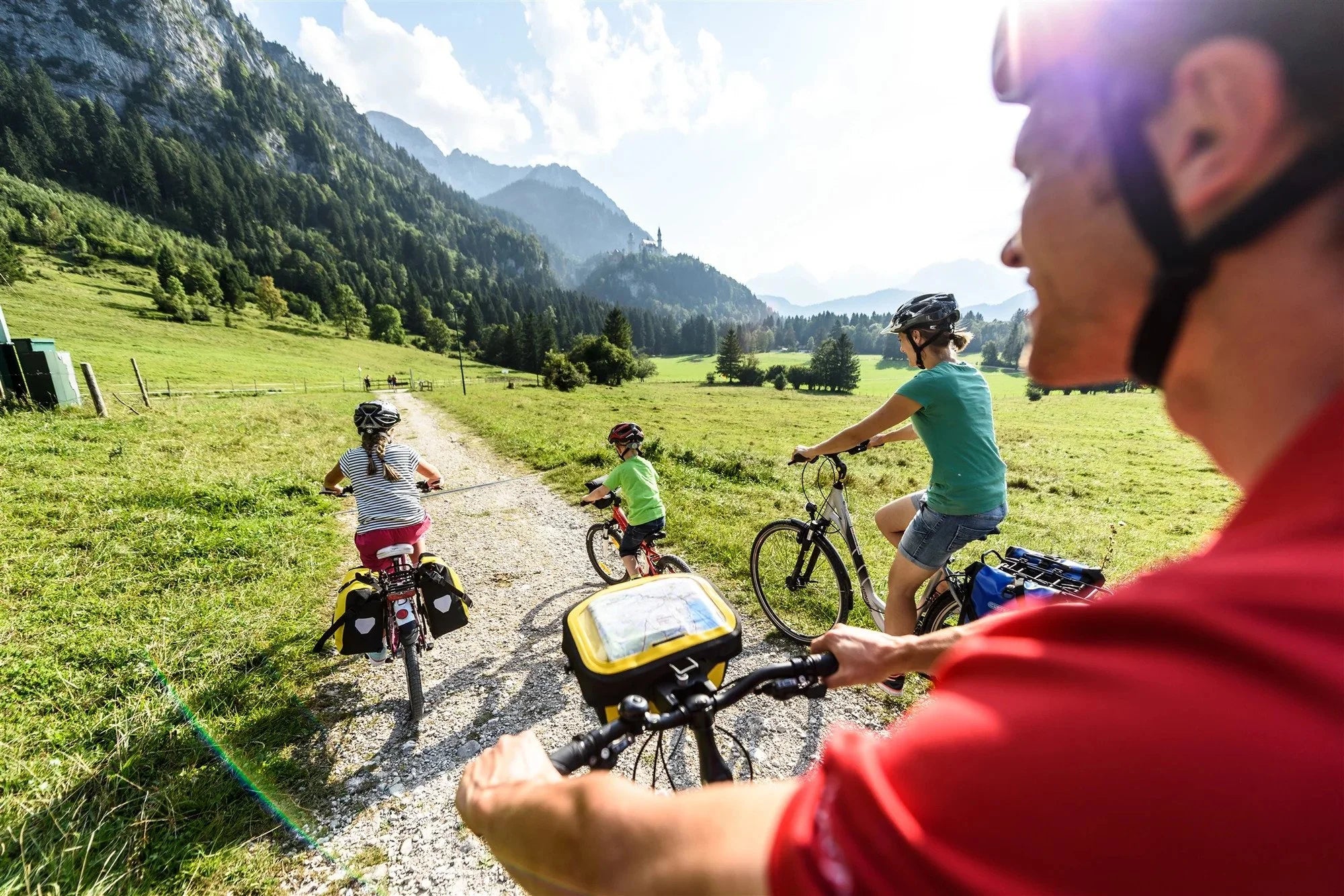 Family cycling on a dirt path with mountains in the background