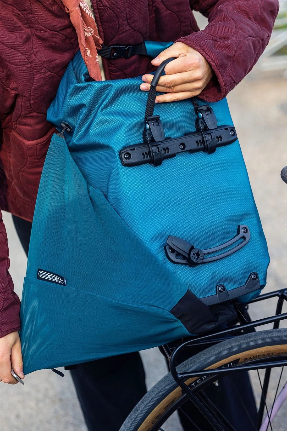 Person holding a blue bike bag on a bicycle