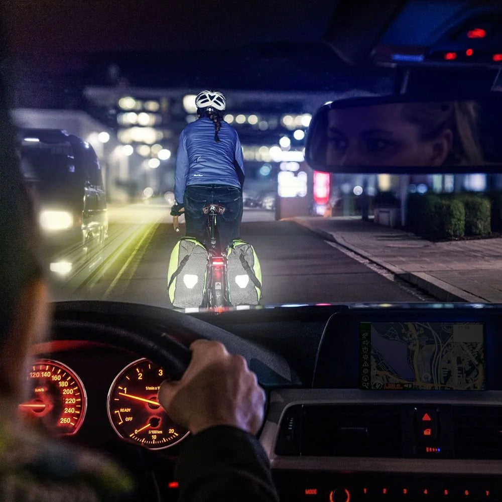 Person driving a car at night with a cyclist on a bike path ahead.