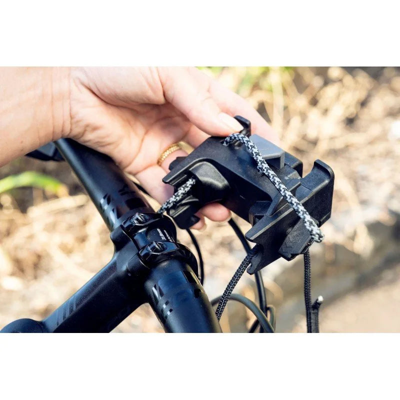 Person adjusting a bike accessory with a blurred natural background