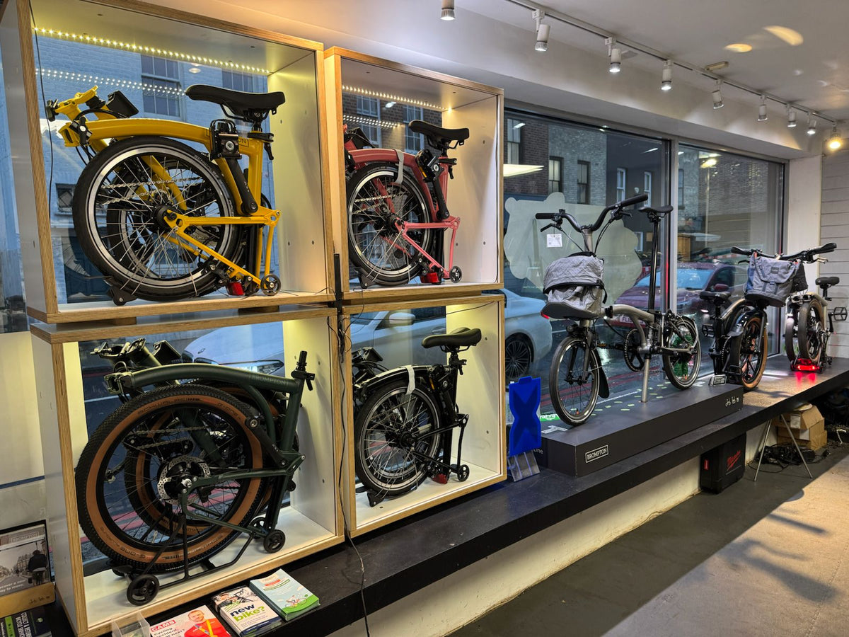 Display of folded bicycles in a store setting with glass cases.