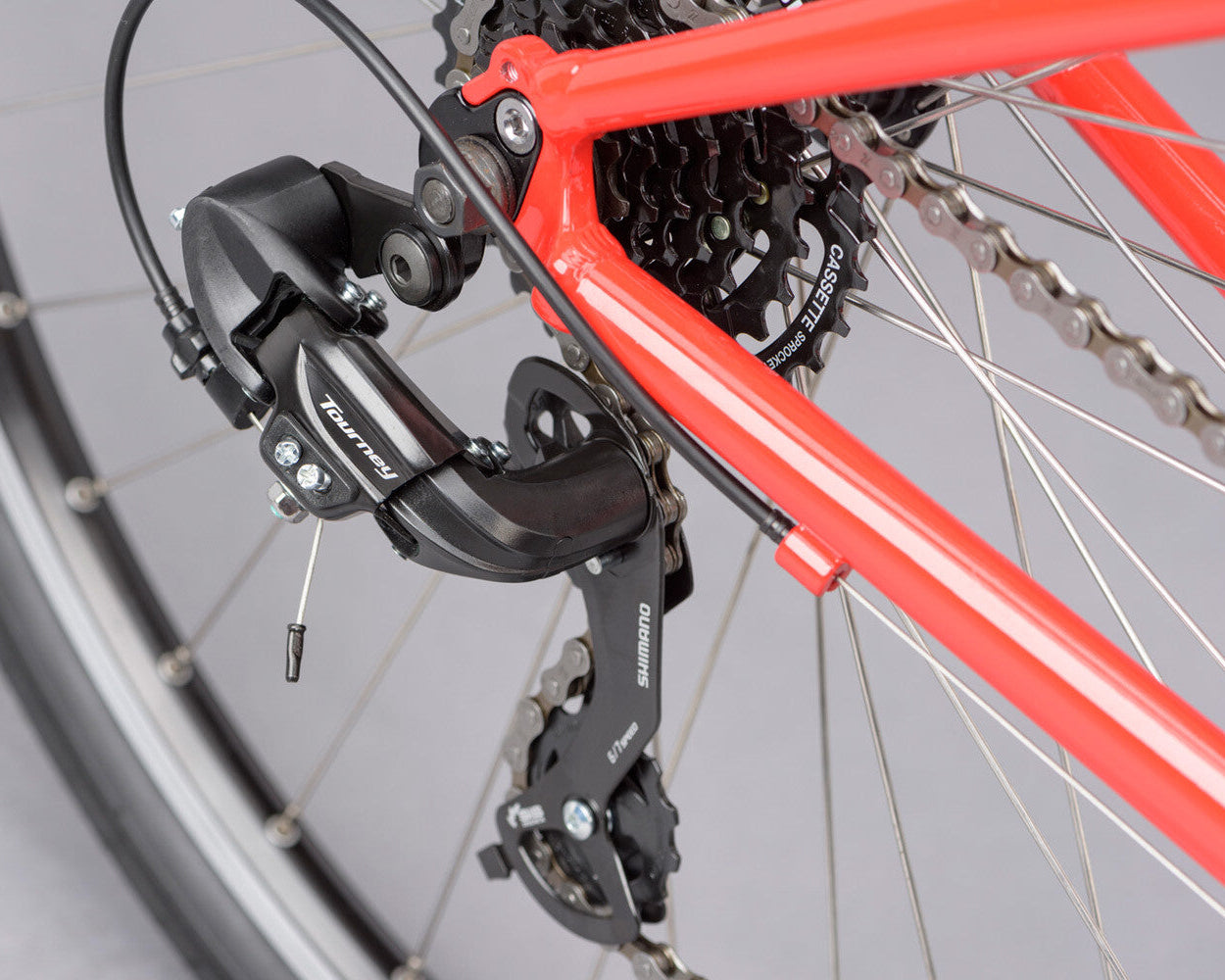 Close-up of a bicycle's rear derailleur and chain on a red frame.