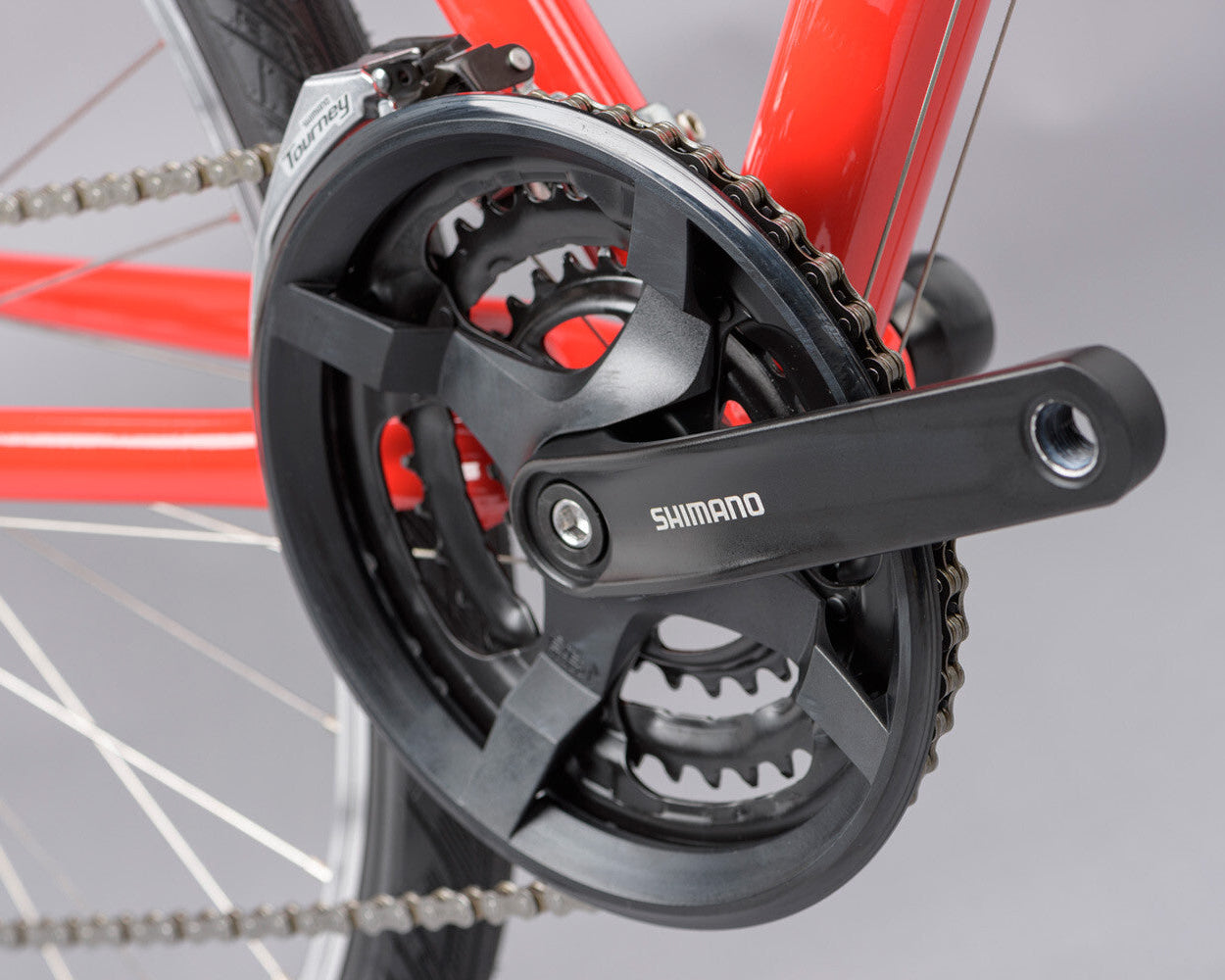 Close up of a bicycle shimano crank and chain ring on a red ridgeback motion.