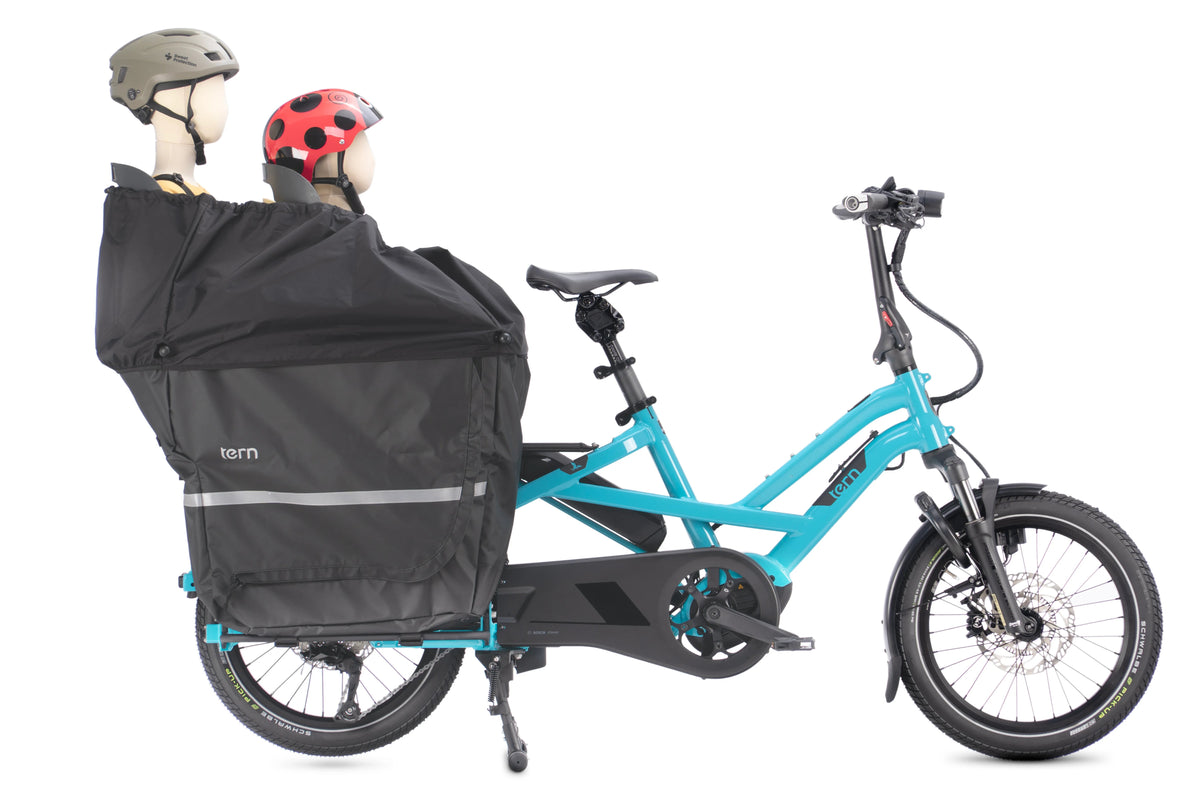 Blue Tern cargo electric bike with black Storm box and two child like mannequins at the back on a white background.