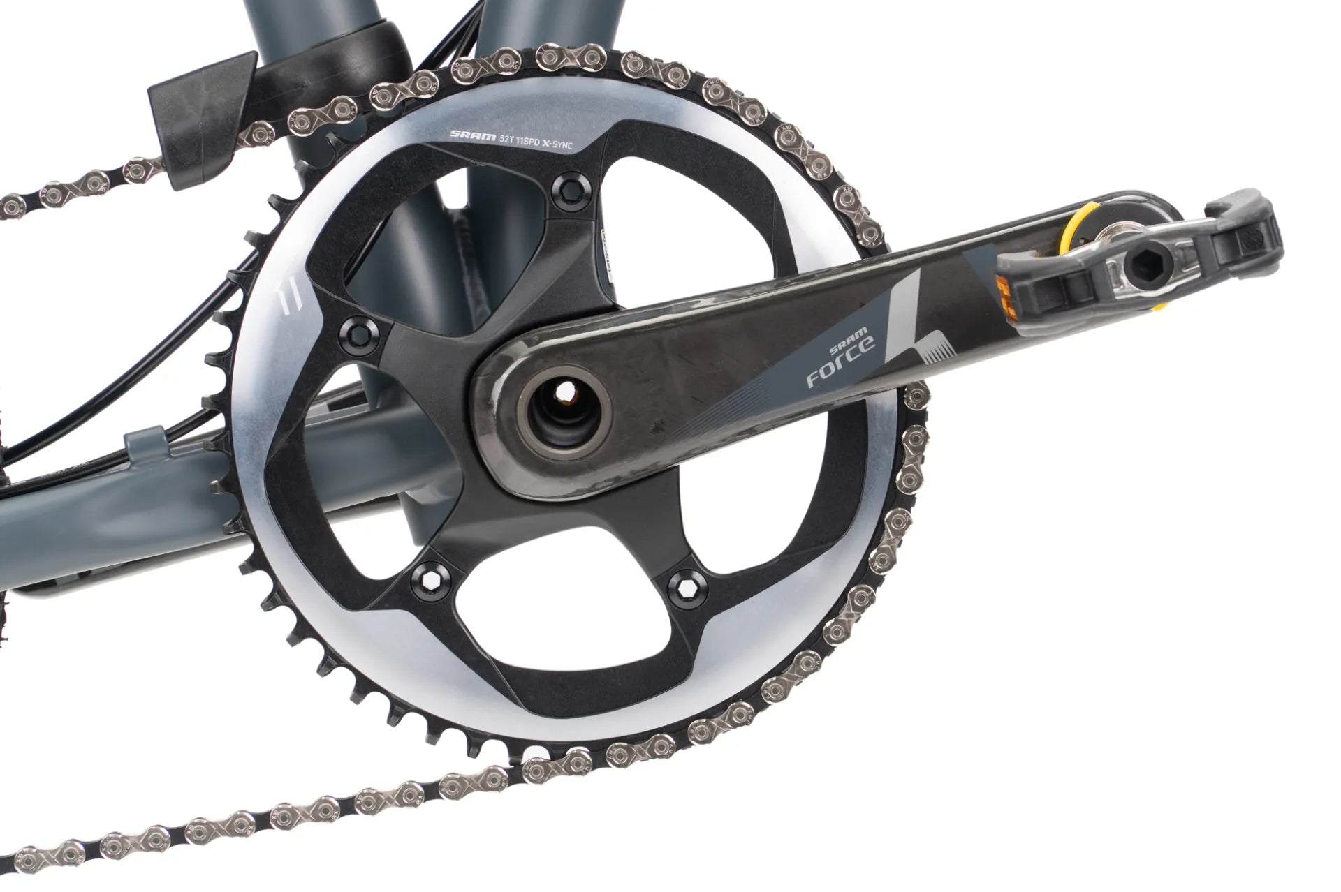 Close-up of a bicycle crankset with a black and silver chainring, black crank arm, and part of the chain visible against a white background.
