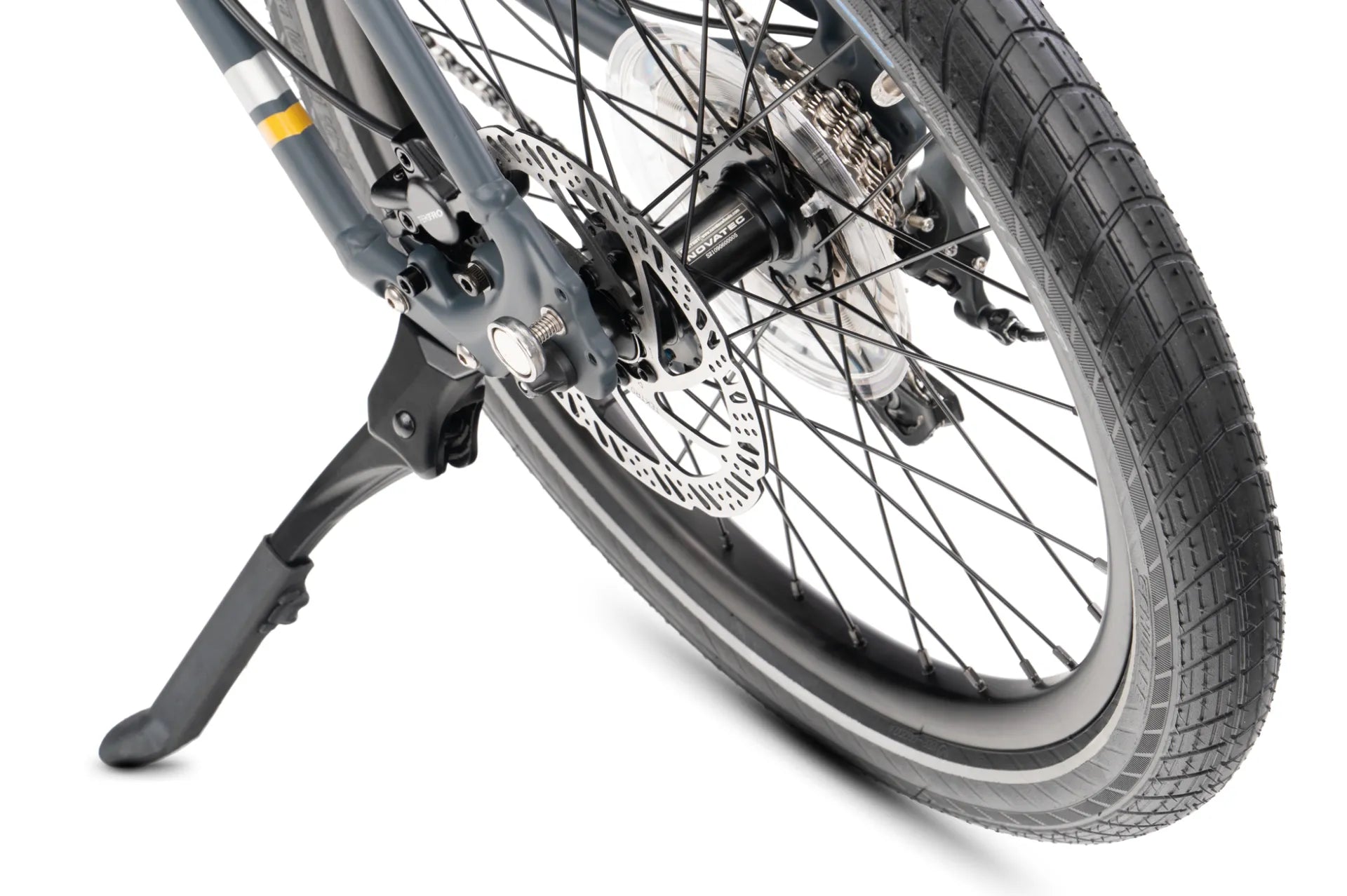 Close-up of a bicycle wheel with a black disc brake, silver spokes, and a black tire, supported by a black kickstand against a white background.
