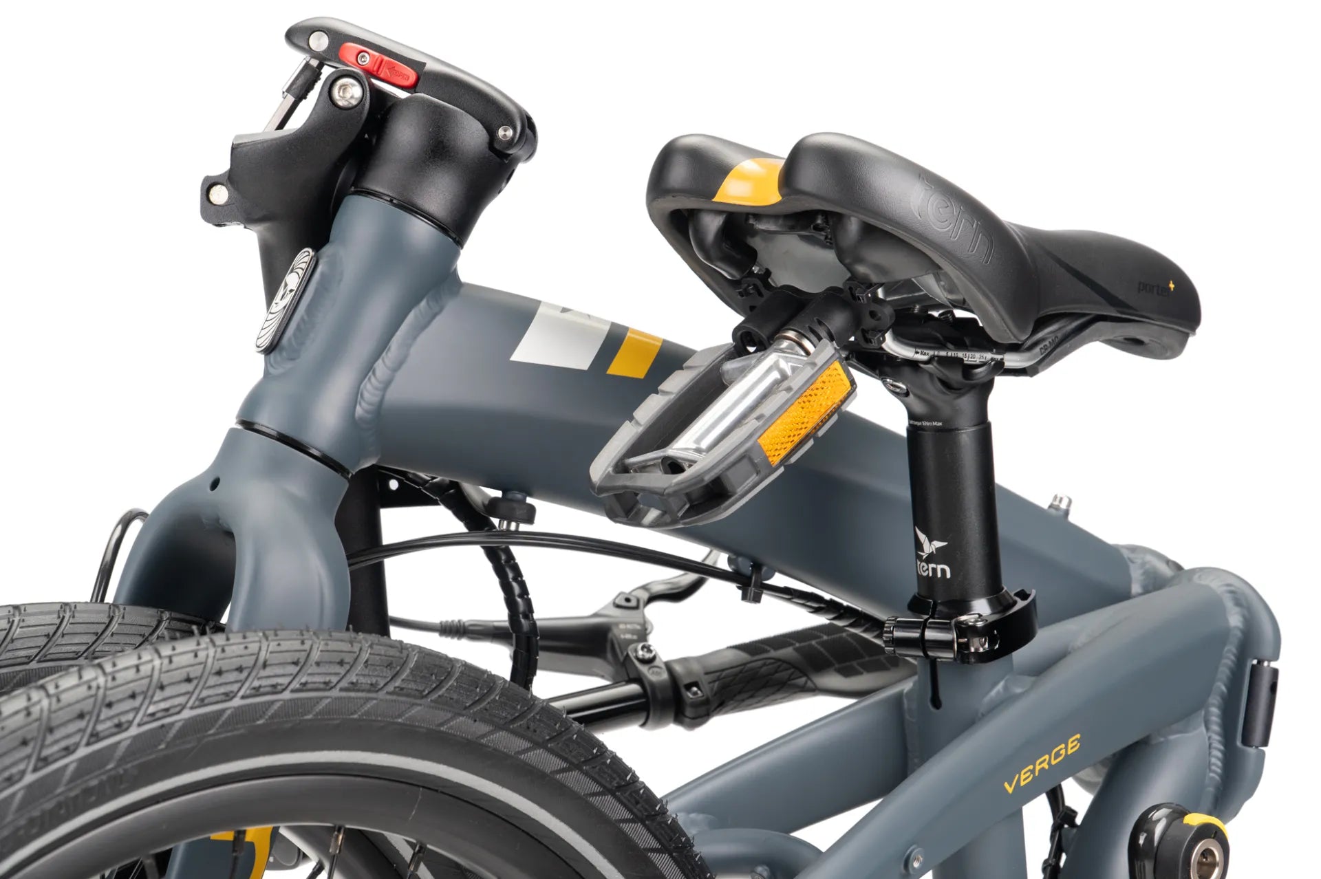 Close-up of a folded bicycle frame in matte dark grey, showing the seat post, saddle, rear rack, and part of the tire against a white background.