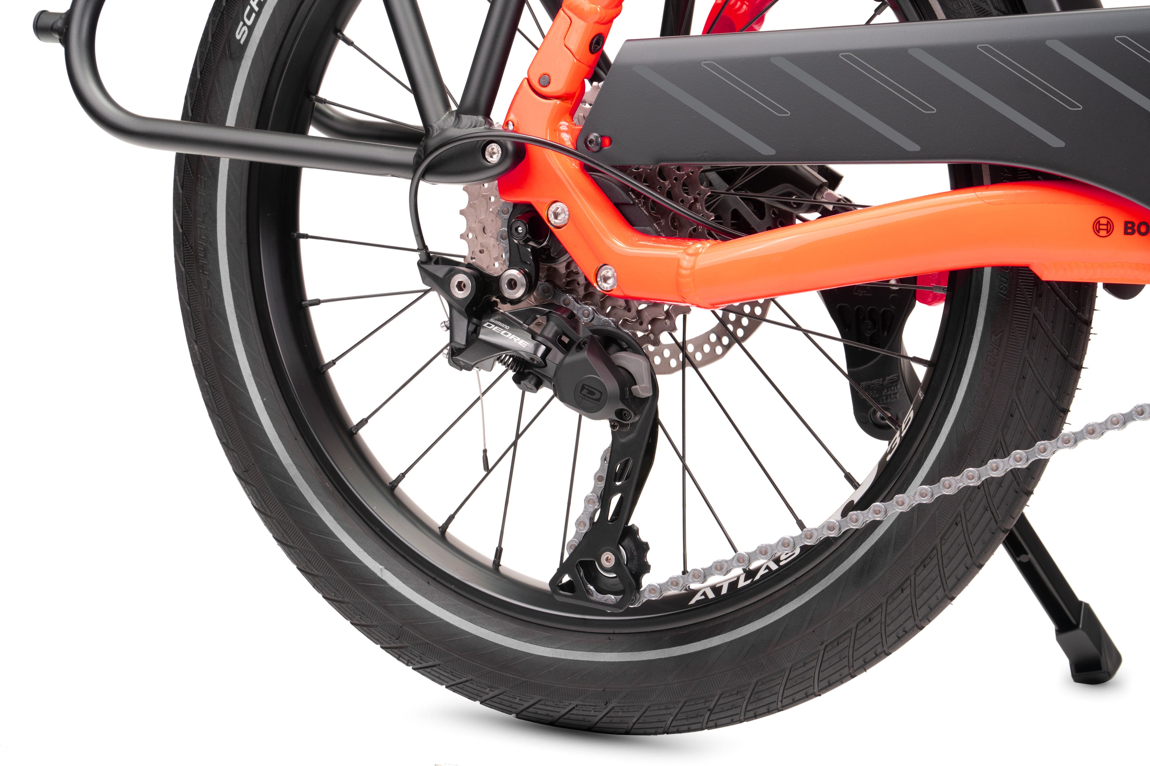 Close-up of an orange cargo bike's rear wheel on white background.