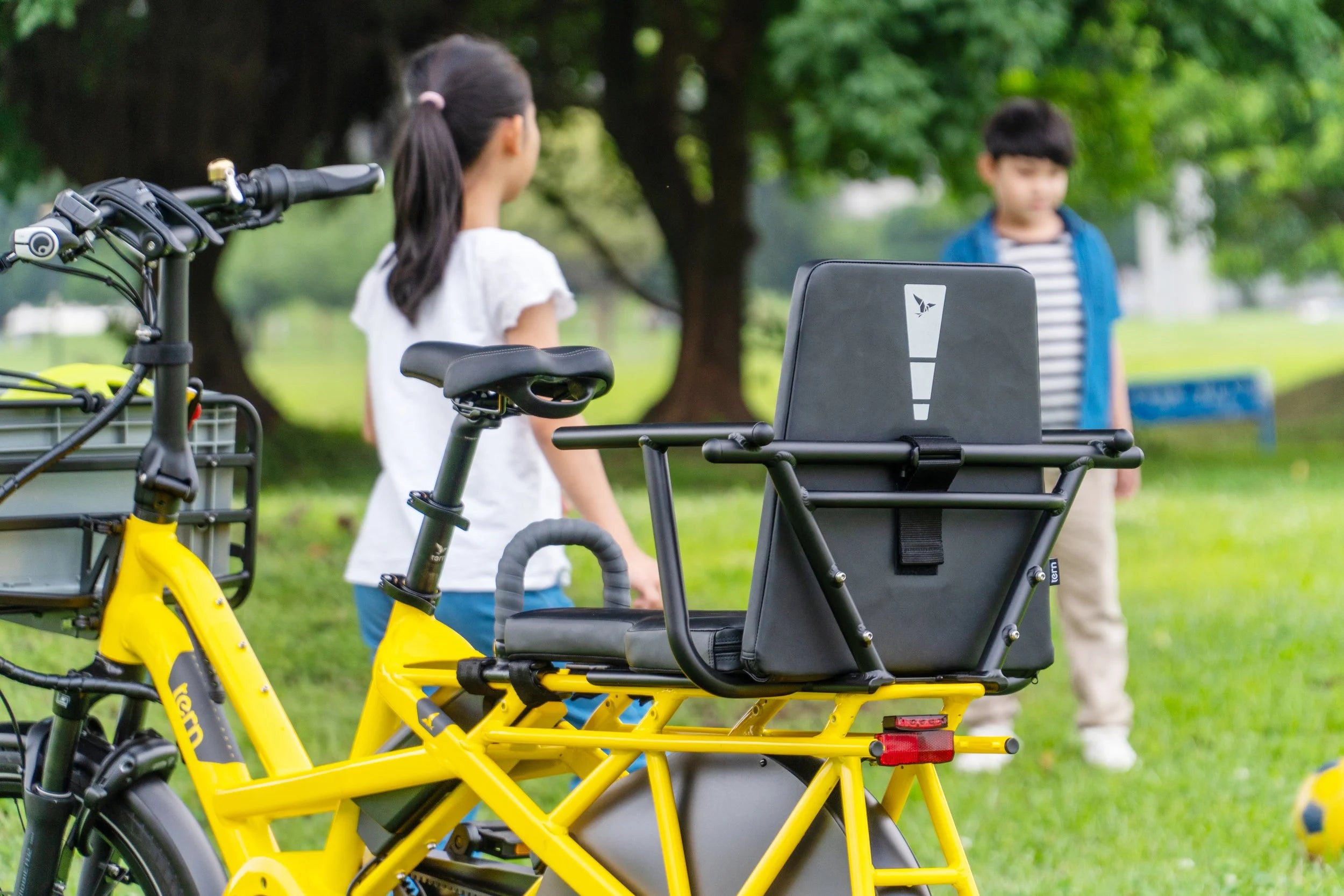 Yellow electric bike with a child seat in a park setting