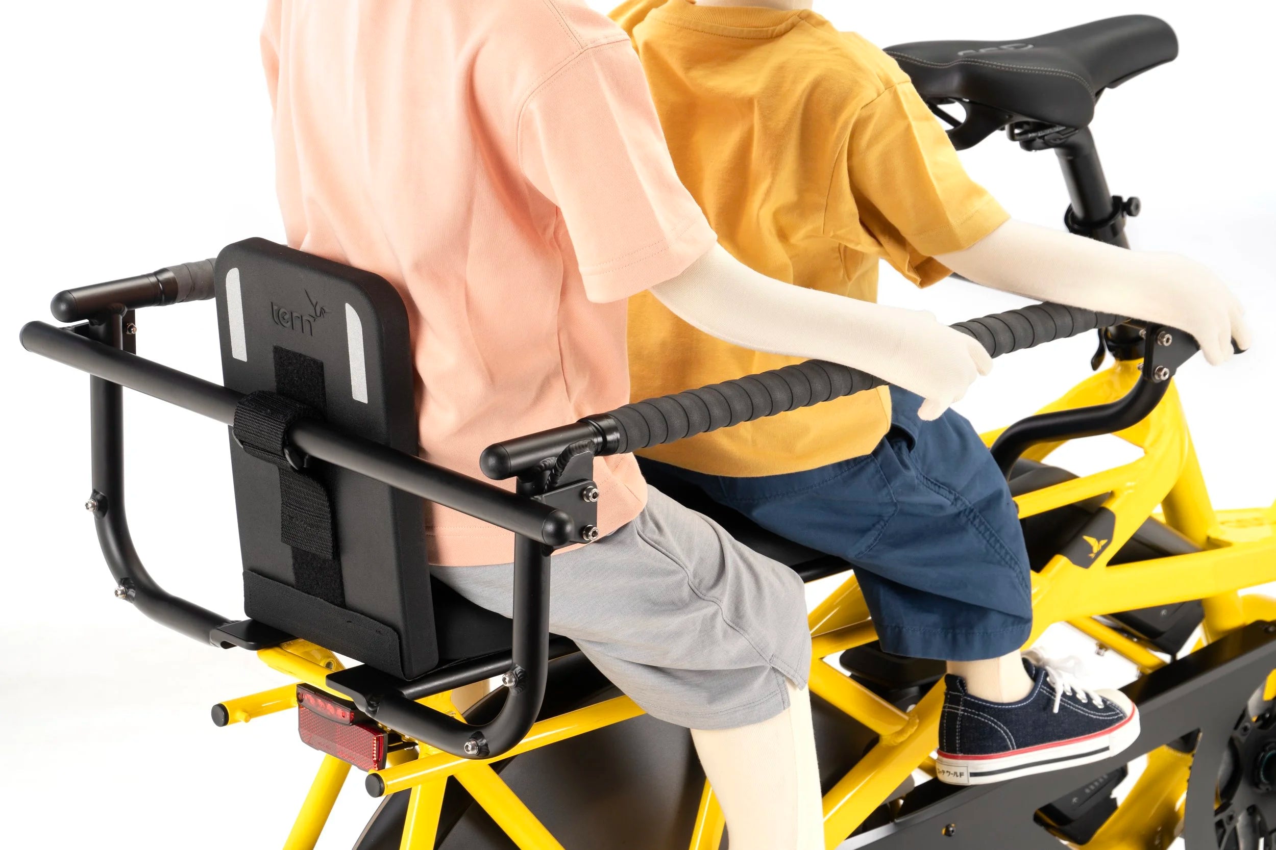 Two pchildren using a yellow electric bike with a child seat on a white background