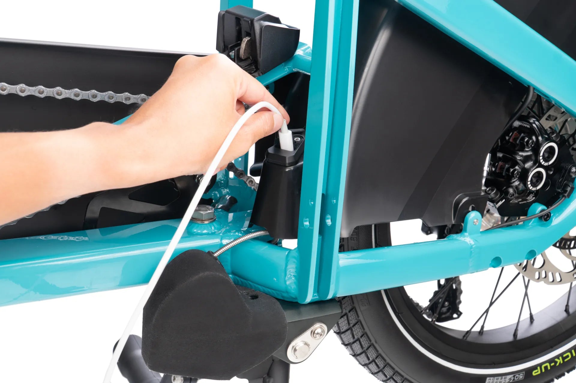 Close-up of a blue cargo bicycle with a person's hand plugging in a cable.