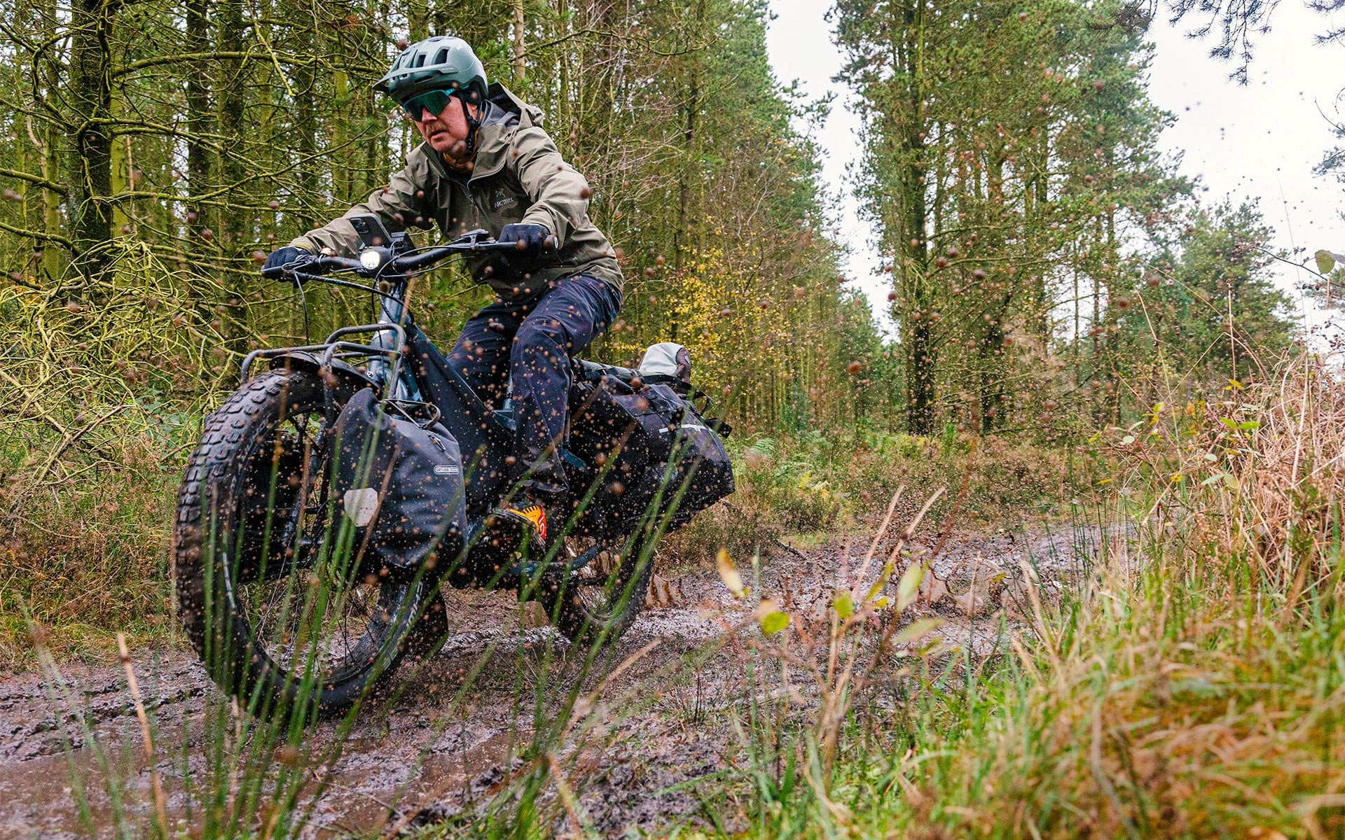 Person riding fat wheel bike through mud.