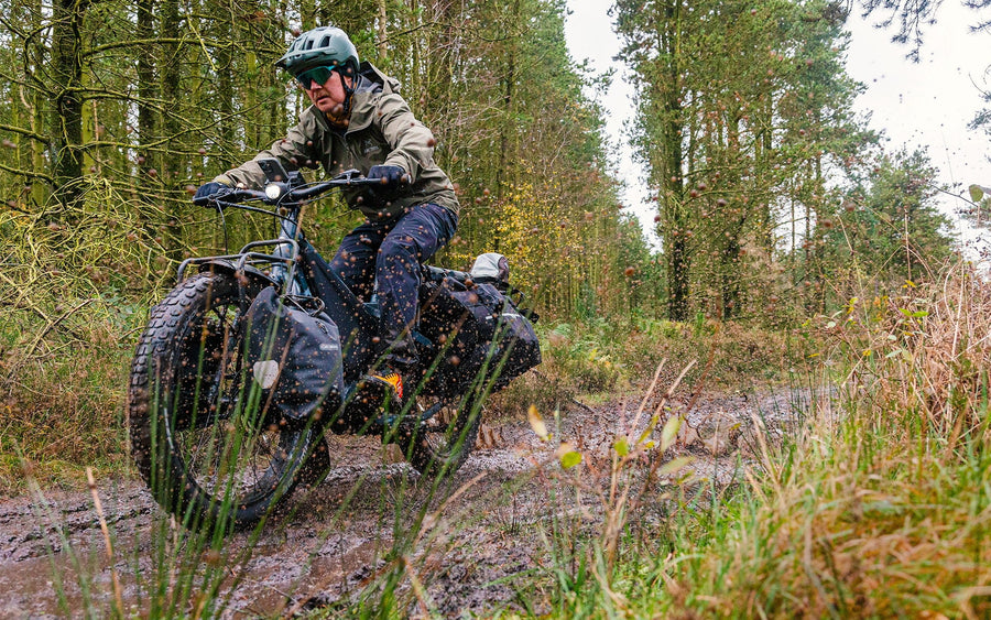 Person riding fat wheel bike through mud.